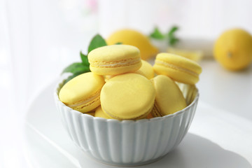 Bowl with tasty lemon macarons on table, closeup