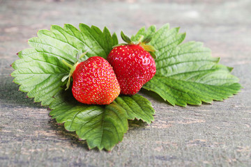 Fresh strawberries with green leafs on grey wooden table