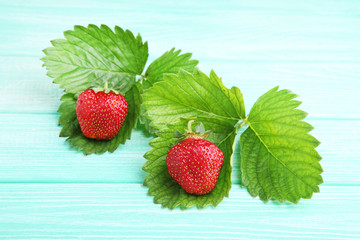 Fresh strawberries with green leafs on mint wooden table