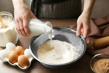 Woman making dough for cinnamon rolls in kitchen