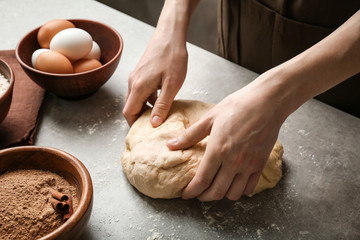 Woman kneading dough for cinnamon rolls on kitchen table