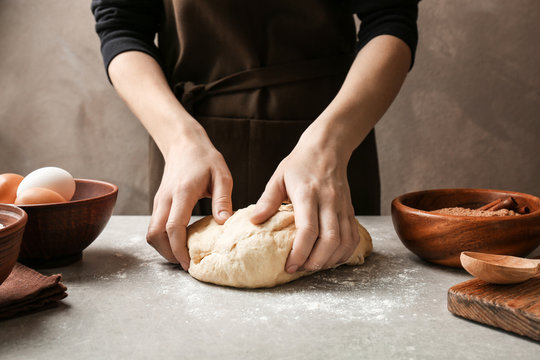 Woman kneading dough for cinnamon rolls on kitchen table