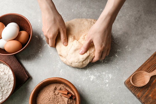 Woman kneading dough for cinnamon rolls on kitchen table
