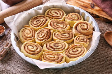 Raw cinnamon rolls in baking pan on kitchen table