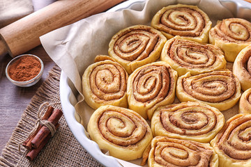 Raw cinnamon rolls in baking pan on kitchen table