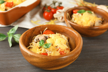 Wooden bowls with delicious roasted turkey tetrazzini on kitchen table