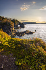Sunset with a natural bridge in view along a coastal area of Green Bay near Langdon's Cove,...