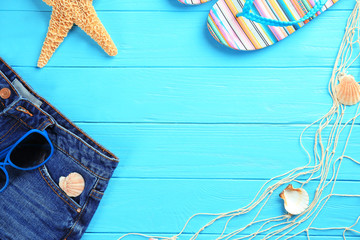 Summer vacation concept. Composition with flip-flops and jeans on color wooden background