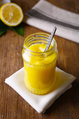 Glass jar with delicious lemon curd on wooden table