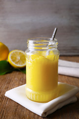 Glass jar with delicious lemon curd on wooden table