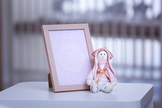 Empty photo frame with toy on table in baby room