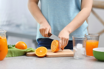 Obraz na płótnie Canvas Woman preparing orange lemonade in kitchen