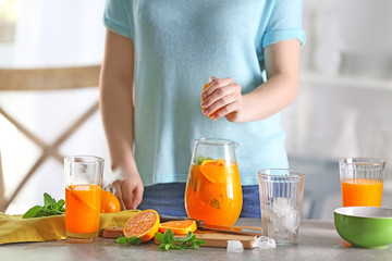 Woman preparing orange lemonade in kitchen
