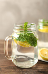 Refreshing lemon water in glass mason jar on wooden table