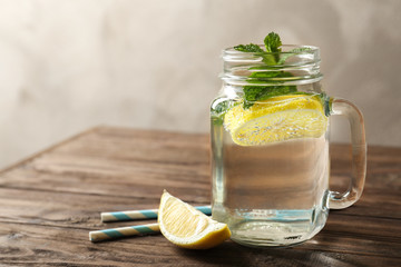 Refreshing lemon water in glass mason jar on wooden table
