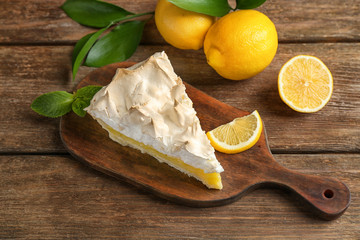 Piece of yummy lemon meringue pie on wooden table