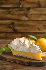 Piece of yummy lemon meringue pie on wooden table