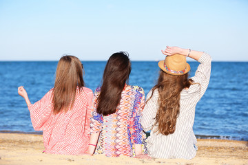 Beautiful young women in beachwear near sea on sunny day
