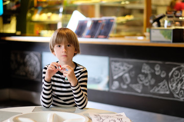 Portrait of a boy with a toy in a cafe