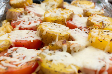 Baked potatoes and tomatoes covered in melted cheese