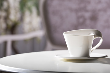 White cup and saucer. On a white table.