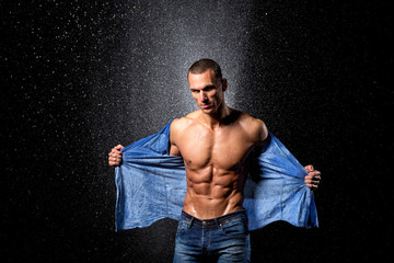 wet fitness muscular male model standing on rain
