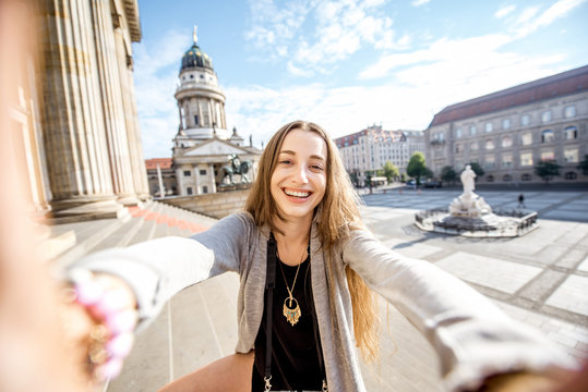 Young and happy woman tourist making selfie photo near the Concert house in Berlin city