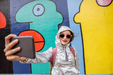 Naklejka premium Młoda kobieta turysta robi selfie zdjęcie stojąc przed murem berlińskim w Niemczech