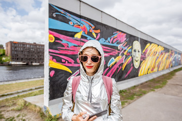 Portrait of a young woman tourist standing in front of the Berlin wall in Germany