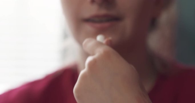 slow motion handheld teen girl taking pill with water