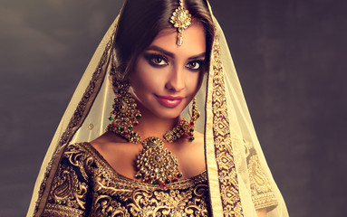 Portrait of beautiful indian girl. Young hindu woman model with golden kundan jewelry set . Traditional Indian costume lehenga choli . 
