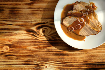 Plate with delicious sliced turkey and sauce on wooden table