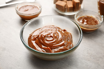Glass bowl with tasty caramel sauce on table