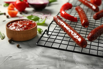 Composition with yummy sausages with sauce on cooling grid, closeup