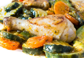 Obraz na płótnie Canvas Fried chicken with vegetables in a frying pan. Chicken legs with barbecue and vegetables close-up background.