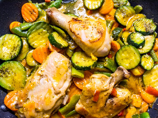 Fried chicken with vegetables in a frying pan. Chicken legs with barbecue and vegetables close-up background.