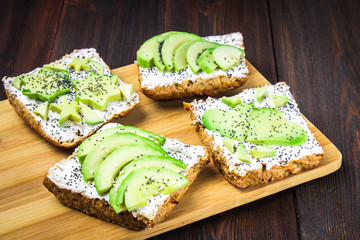 Sandwiches from bread with slices, zvezdami, hearts from avocado and curd cheese on a brown wooden background.