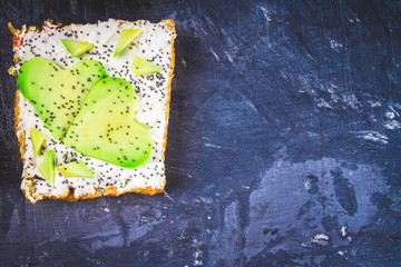 Sandwiches from bread with slices, zvezdami, hearts from avocado and curd cheese on a gray dark marble background.
