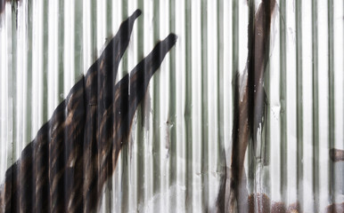 Texture of fence from corrugated iron with graffiti detail. Silvery wall from a wavy metal sheet...