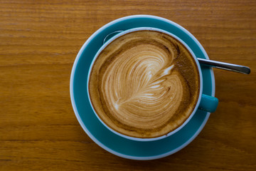 Hot coffee in green cup on wooden background.