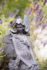 A fairy statue in a garden of purple flowers