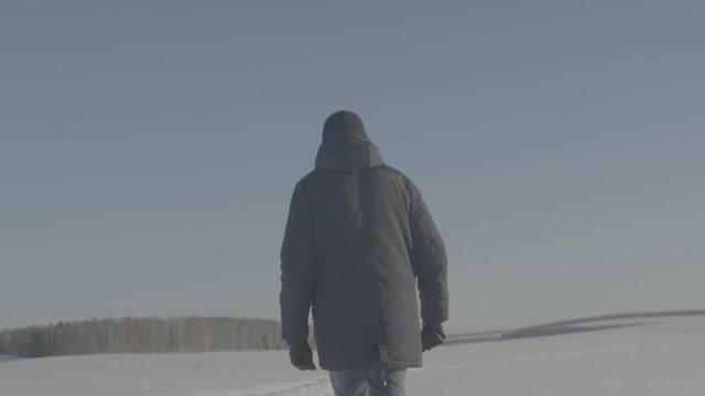 Man goes through the snowy field. A person on a snowy field. Man walking on deep snowy field