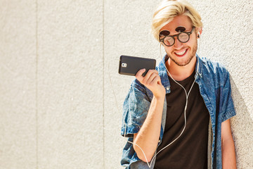 Fototapeta premium Hipster man smiling listening music through earphones
