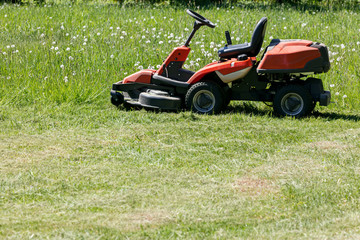freshly cut grass by red lawnmower. gardening background.