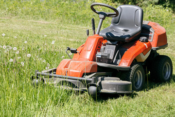 red lawn mower on green grass lawn in sunny day closeup