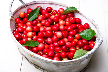 Red cherries in white basket on white wooden background. Cherry close up.