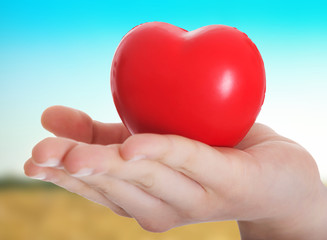 Red heart held on a female's hand.
