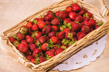 Strawberry in a wooden basket rests on a wooden table