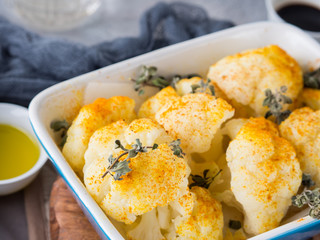 Baked cauliflower with turmeric and marjoram on rustic background. Lunch with vegetables
