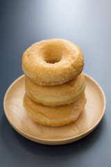 Sugary donuts on a wooden plate on a dark table background. in a Morning light. Breakfast concept